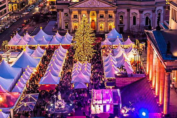 Luftaufnahme des Weihnachtsmarkts auf dem Gendarmenmarkt in Berlin zeigt weiße Zelte und ein großer geschmückter Weihnachtsbaum