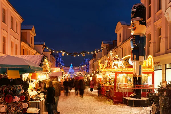 Auf dem Weihnachtsmarkt in Potsdam stehen eine große Nussknacker-Statue, verschiedene Stände mit Waren und festliche Lichterketten.