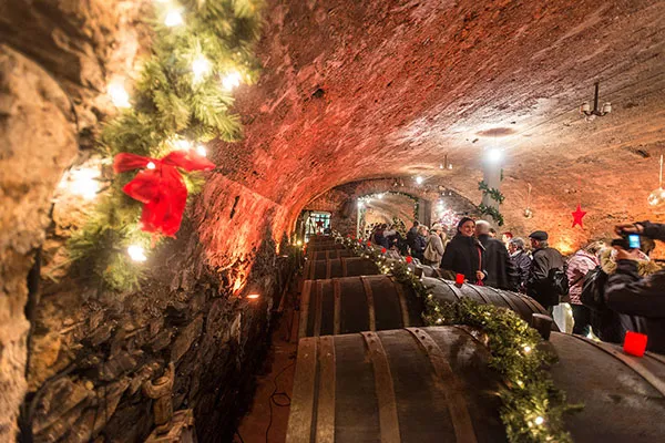 Menschen im weihnachtlich geschmückten Gewölbekeller besuchen den unterirdische Mosel-Wein-Nachts-Markt in Traben-Trarbach