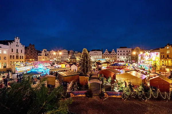 Stände und festliche Lichter auf dem Weihnachtsmarkt in Wismar am Abend.