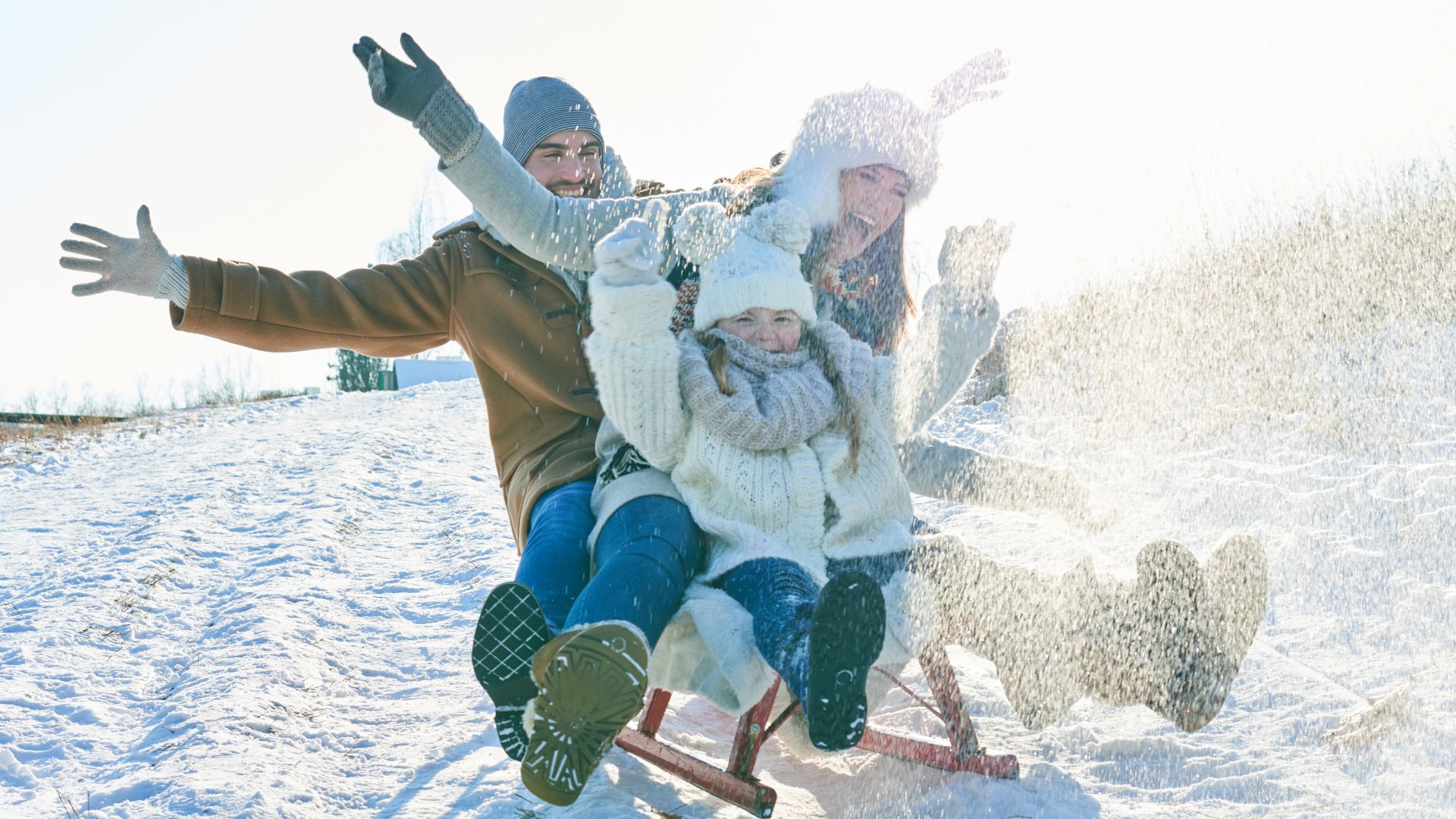 Happy Family Sledding On Snow Covered Field