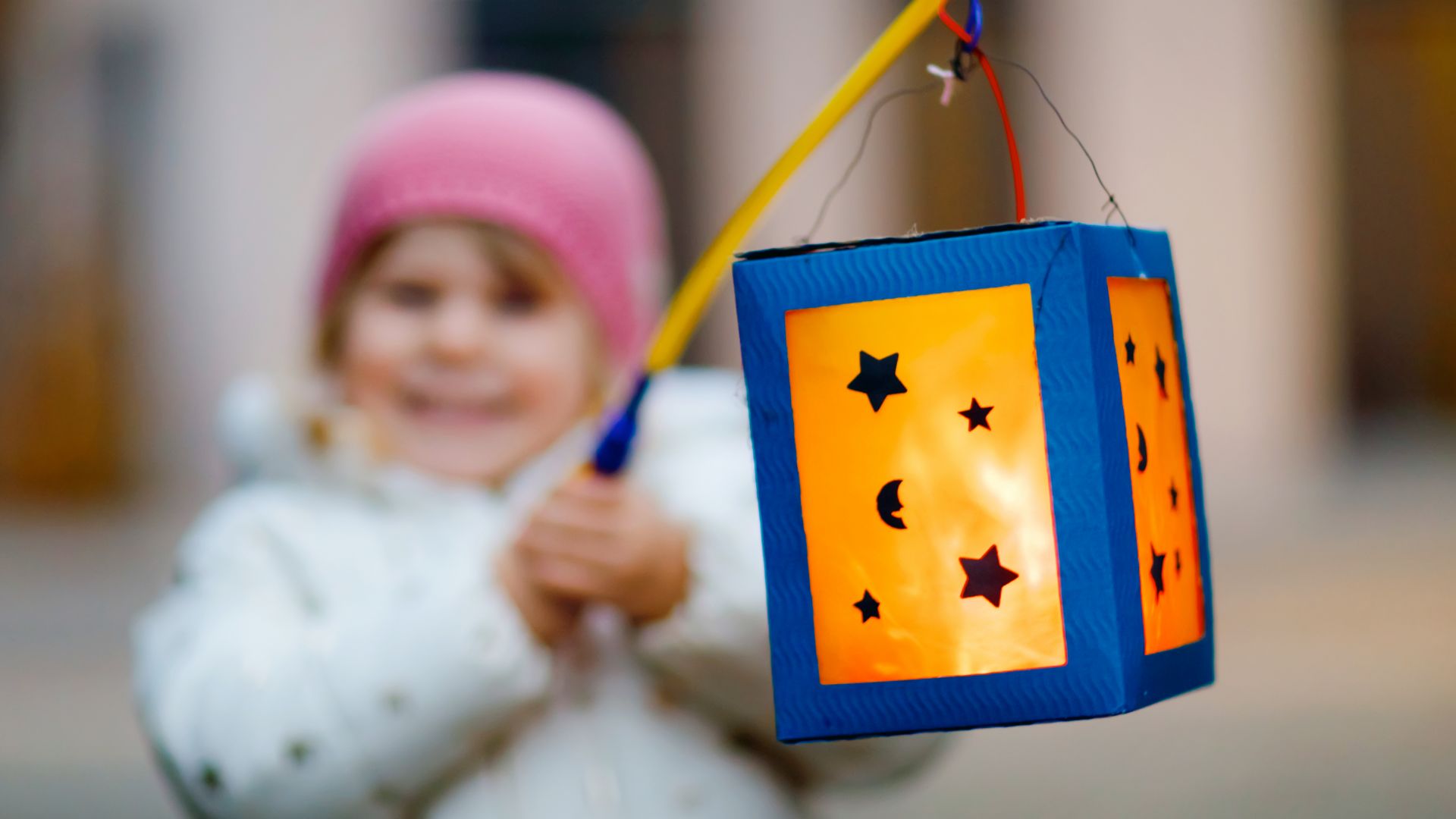 Niña con gorro rosa lleva una linterna luminosa para la procesión de San Martín.