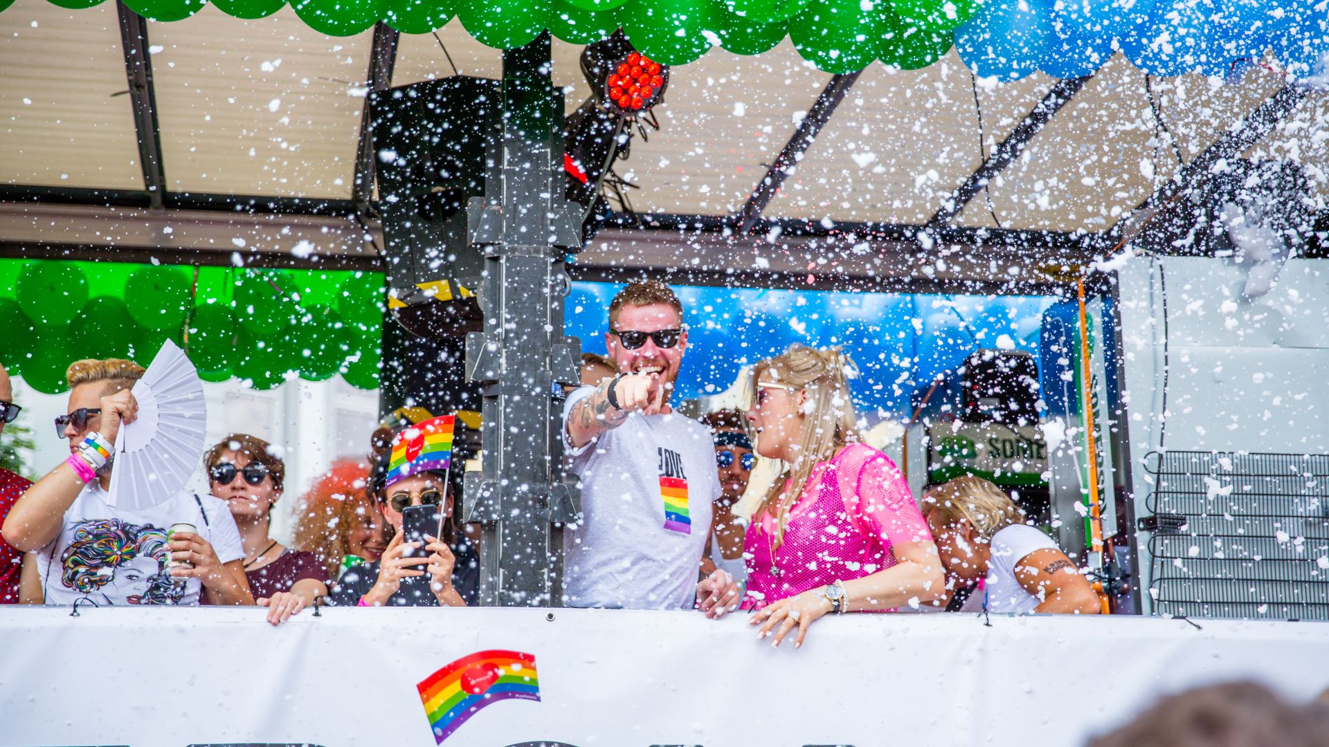 Eine Gruppe von Menschen auf einem mit grünen und blauen Luftballons geschmückten Wagen auf der Hamburger Christopher Street Day Parade