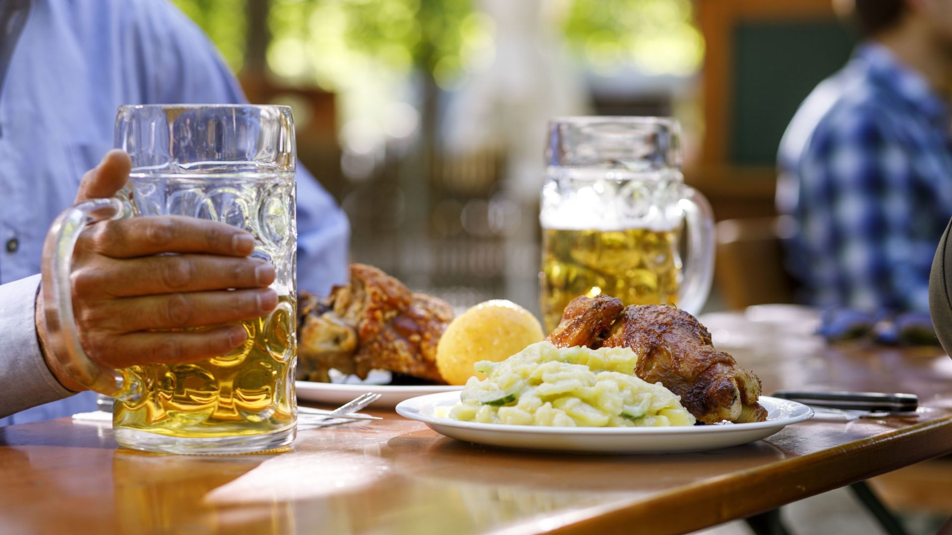 Auf einem Holztisch stehen zwei Teller mit je einer Portion gebratener Schweinshaxe.