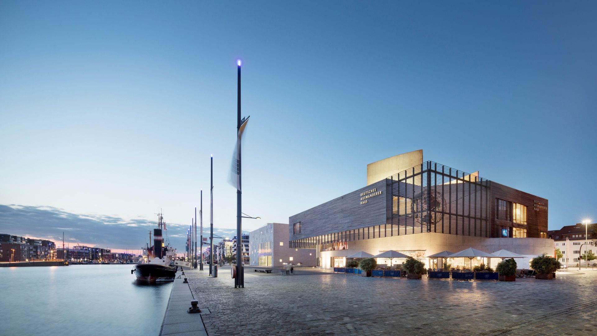 Das Deutsche Auswandererhaus in Bremerhaven steht in der Nähe des Wassers, wo mehrere Boote am Kai festgemacht haben.