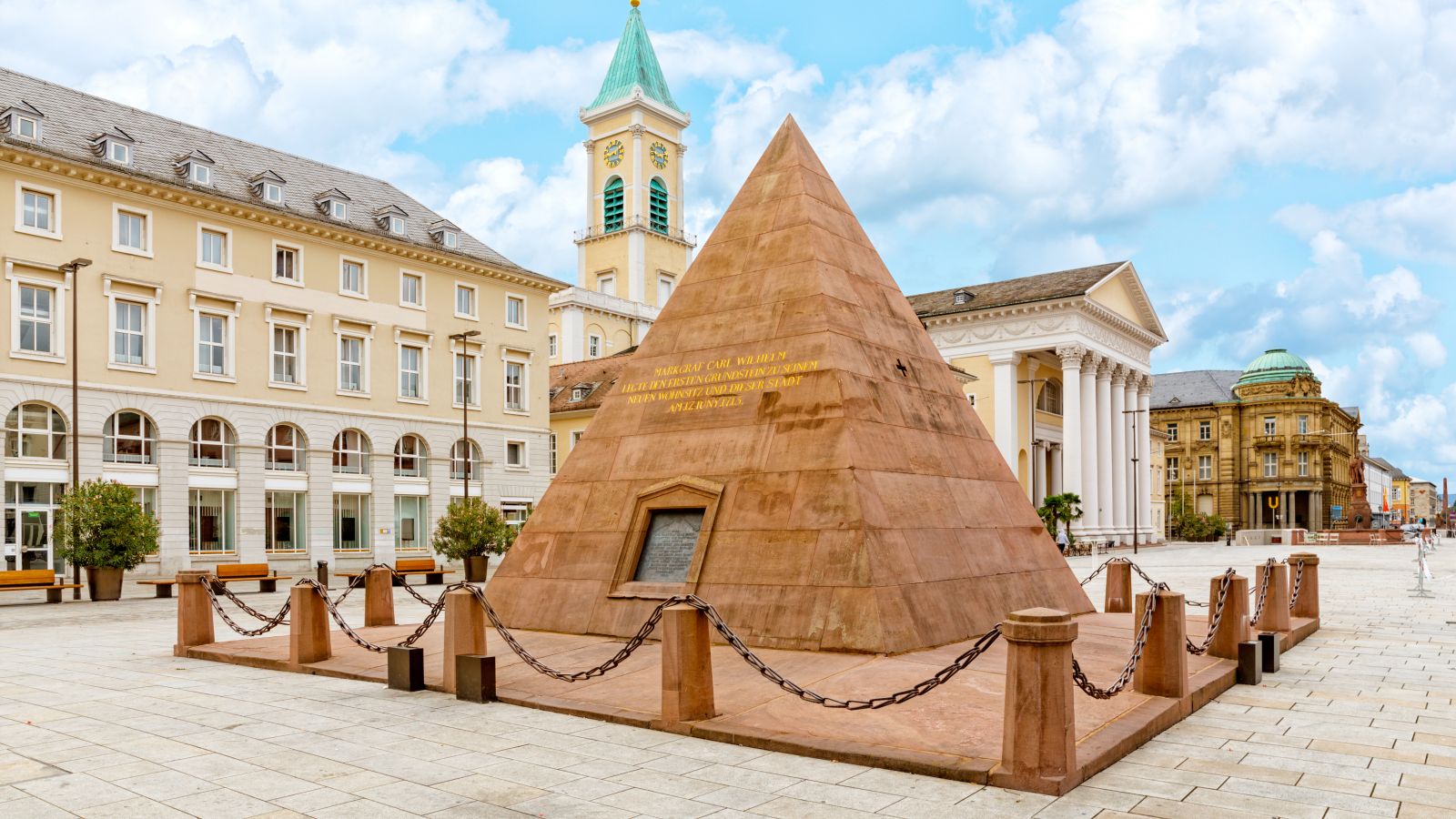 Pyramide en grès sur la place du marché de Karlsruhe, avec des bâtiments historiques et l'église de la ville en arrière-plan