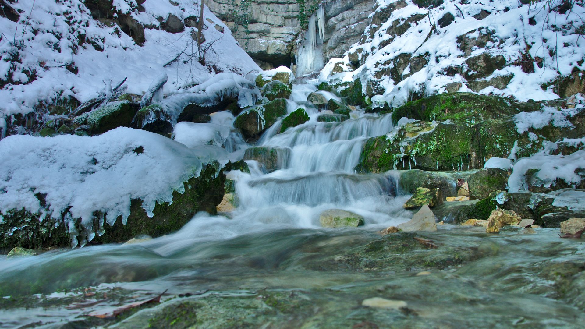 Neidlinger Wasserfall im UNESCO Geopark Schwäbische Alb in Neidlingen fließt die moosbewachsenen Felsen hinunter. Schnee bedeckt im Winter die Felsen und Pflanzen am Wasserfall.