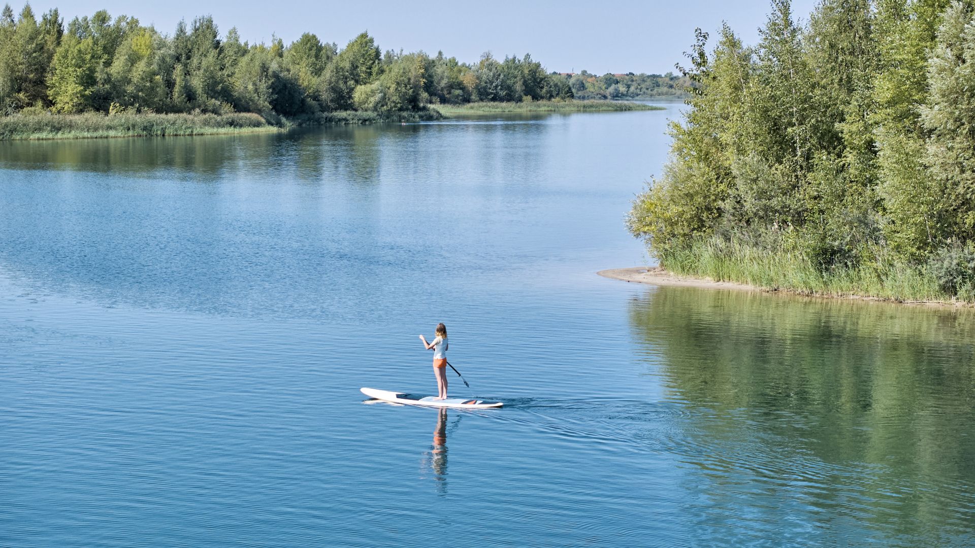 Una mujer practica surf de remo en el lago Markkleeberg en un día de verano.