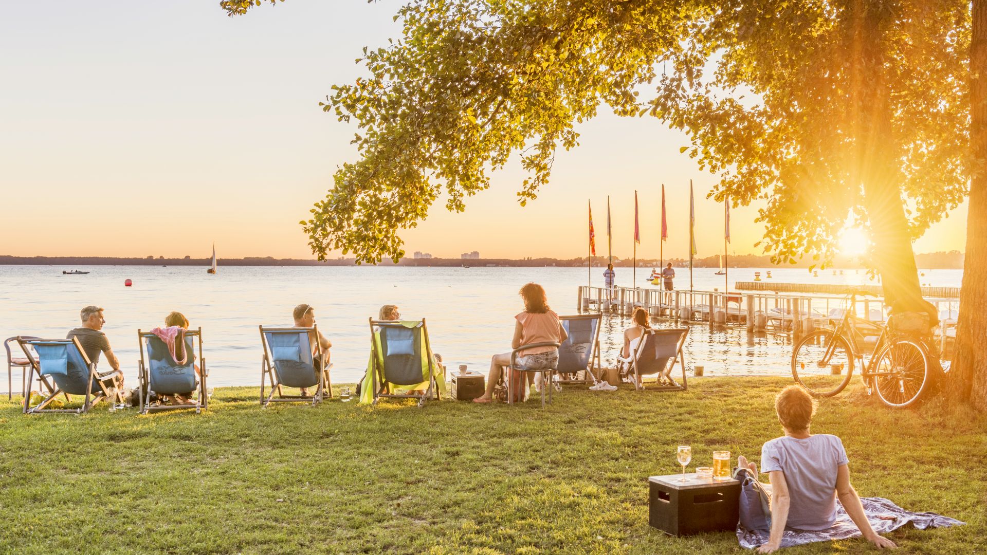 Menschen auf Liegestühlen genießen einen sonnigen Tag am Müggelsee in Berlin