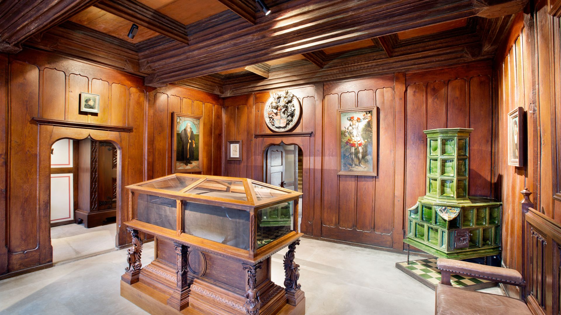 Ein Raum im Luthers Sterbehaus in Eisleben mit Holzwänden und -decken. Eine Holzkonstruktion mit Glasscheiben In der Mitte.