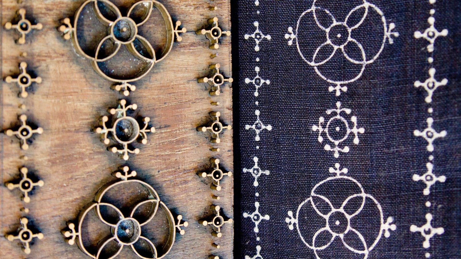 Printing block next to a piece of blue fabric printed with the same pattern