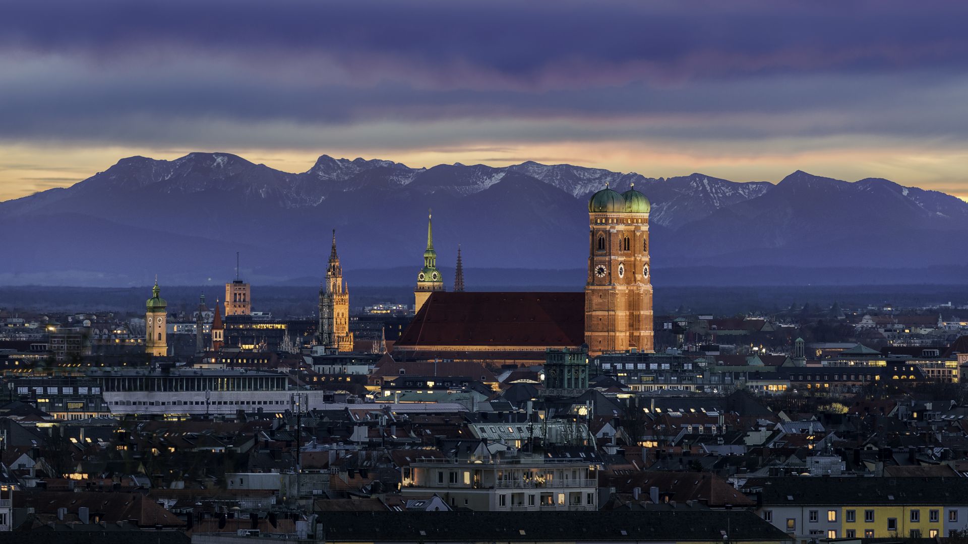 München: Sonnenuntergang mit Frauenkirchen und Alpen im Hintergrund