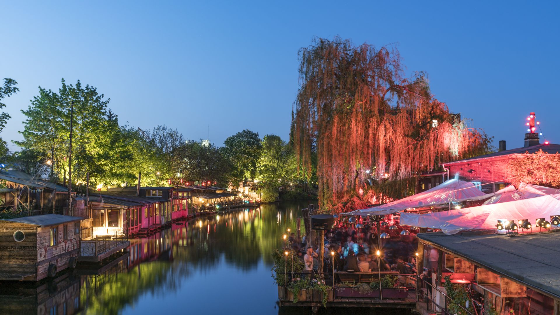 Clubs junto al canal iluminado del Spree en Kreuzberg con luces nocturnas y reflejos en el agua