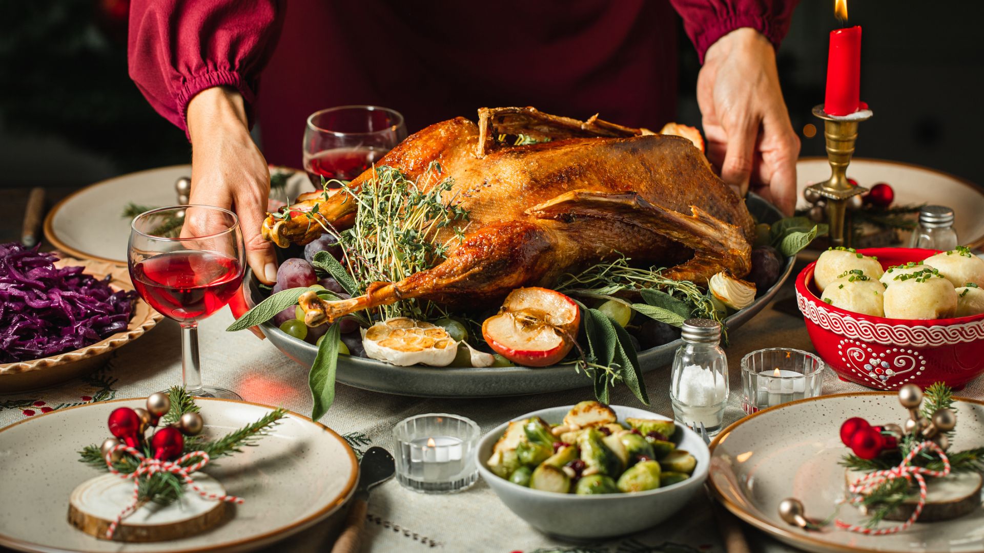 Une femme met la table pour le dîner de Noël avec une oie rôtie