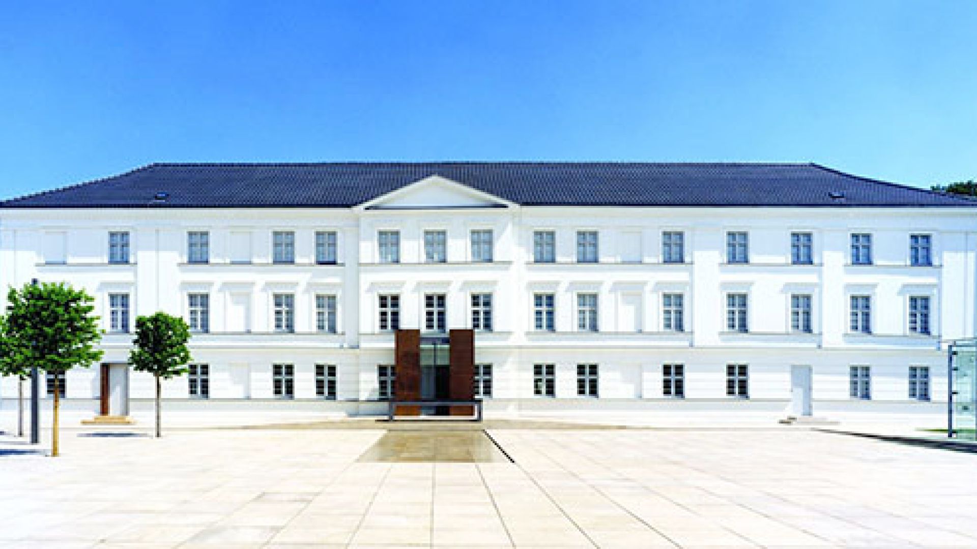 Die Vorderseite vom Pommersches Landesmuseum in Greifswald hat eine weiße Fassade. Das Dach ist dunkel. Der Himmel ist klar und blau.