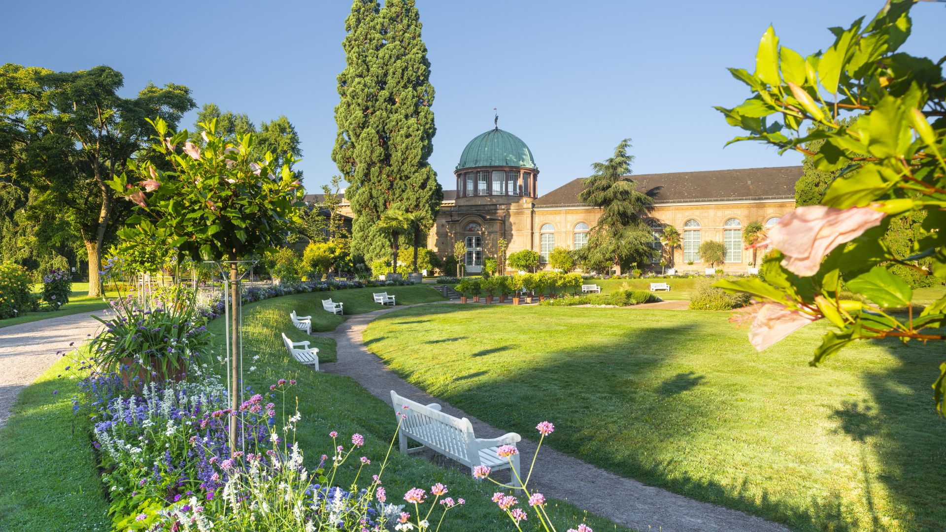 Blumenbeete und historische Gewächshäuser im Botanischen Garten Karlsruhe bei Sonnenschein