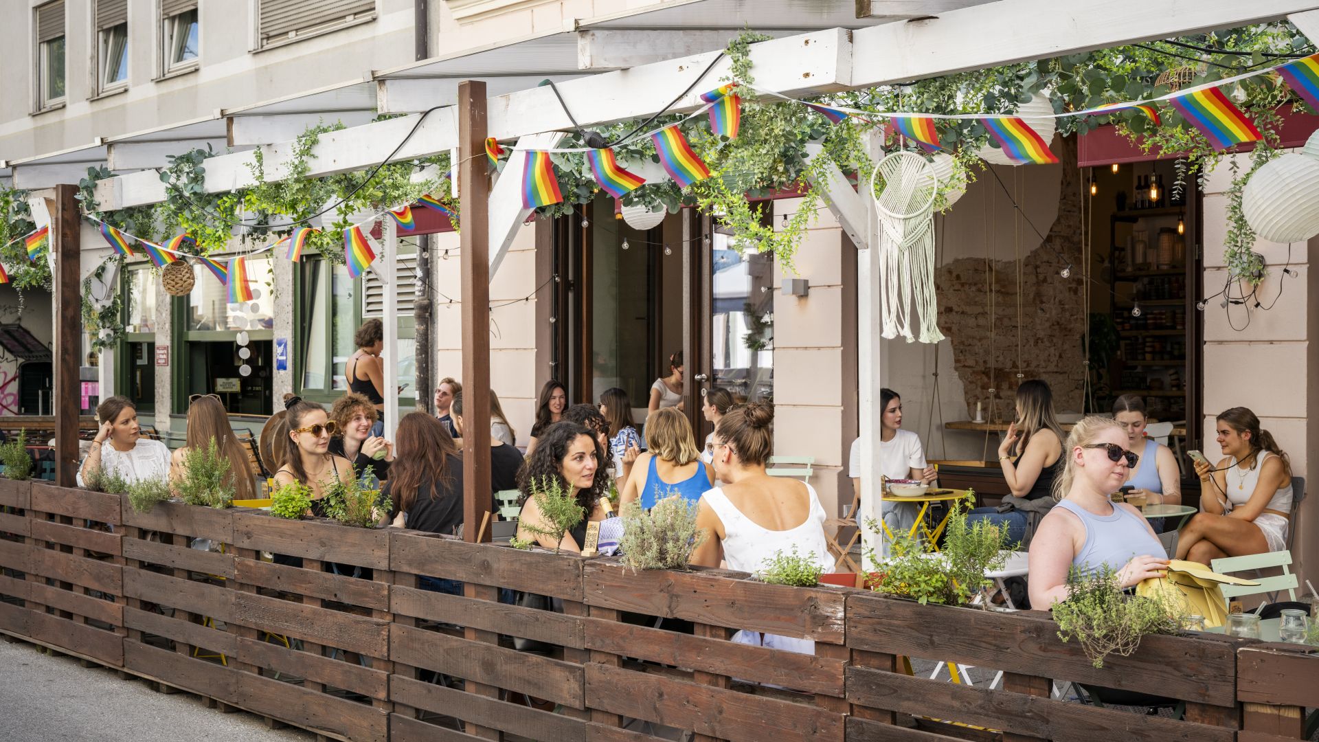 Junge Menschen sitzen bei Sommerwetter in einem Café im Glockenbachviertel in München.
