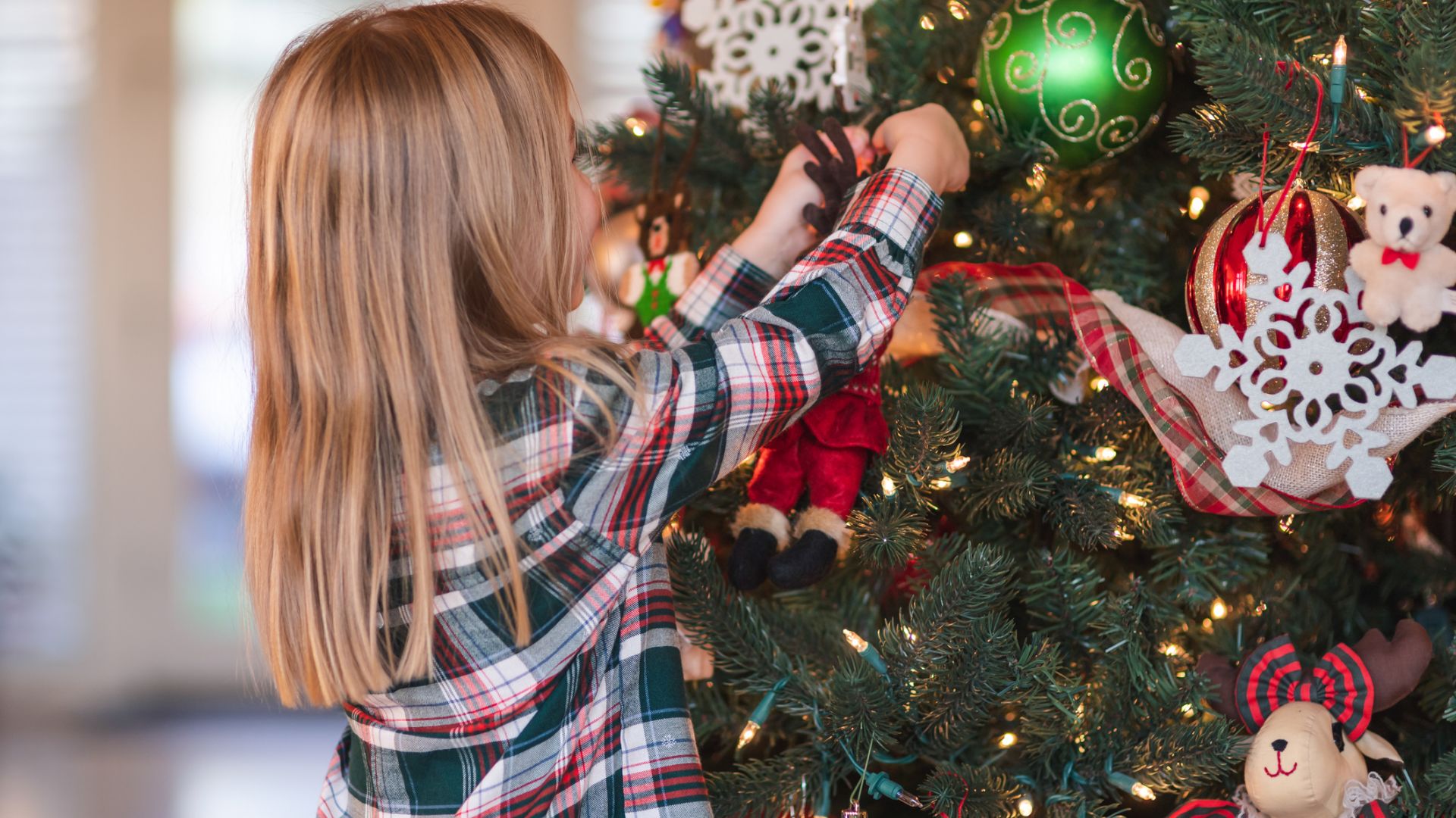 Girl hangs ornaments on the Christmas tree