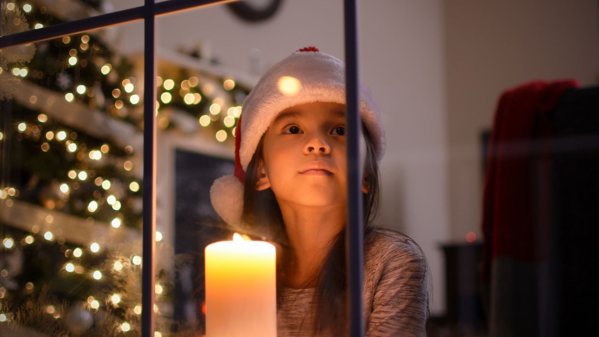 Advent: Mädchen schaut aus dem Fenster, Kerzen in der Weihnachtszeit