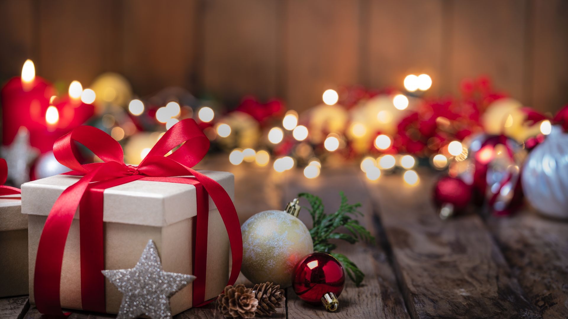 Ein eingepacktes Geschenk mit einer roten Schleife liegt auf einem Holztisch.